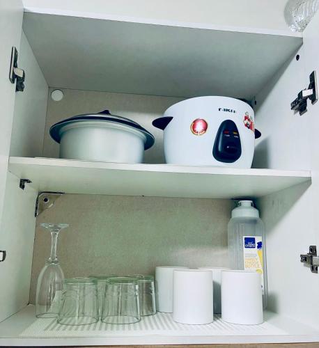 a kitchen shelf with dishes and a blender and other items at RiverBay 2 BR Apartment Naga City in Naga