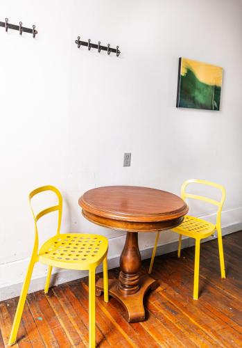 a wooden table and two yellow chairs in a room at The Cambie Hostel Gastown in Vancouver