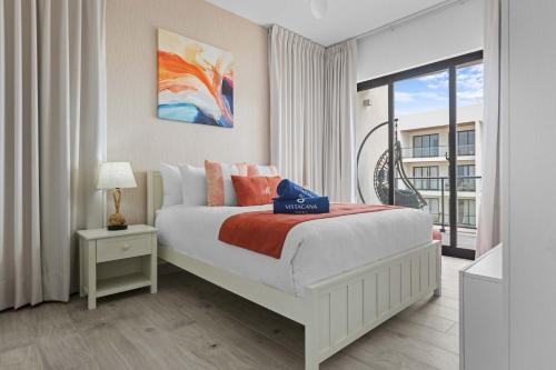 a white bedroom with a bed and a balcony at NOK Elegant 2BR Apt by Vistacana in Punta Cana