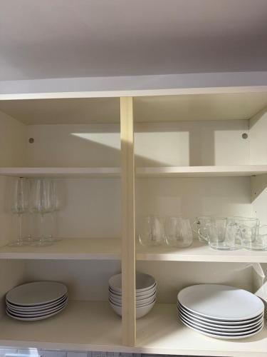 a kitchen with white plates and glasses on shelves at Relaxing Coastal Flat, Perfect Location in Southbourne