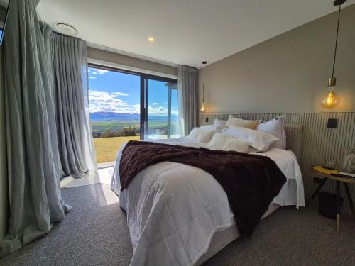 a bedroom with a large bed and a large window at Bendigo Ridge - Where Activity is Relaxing in Cromwell