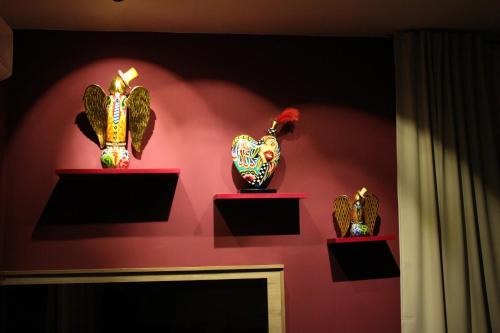 three vases on display on a pink wall at Conte Luxury Rooms in Salerno