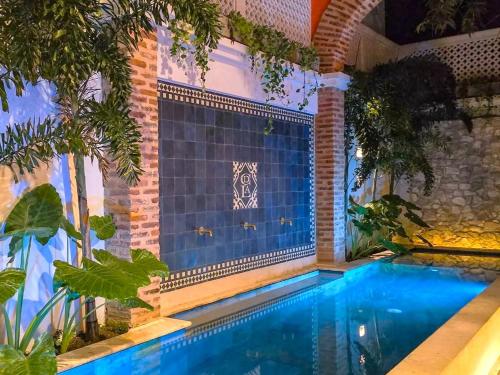 a swimming pool in the middle of a garden at Hotel Casa de la Acequia in Santa Marta