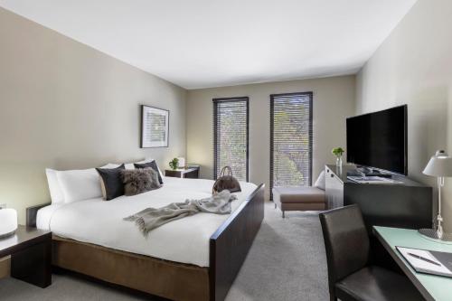 um quarto com uma cama, uma secretária e uma televisão em Lancemore Mansion Hotel Werribee Park em Werribee