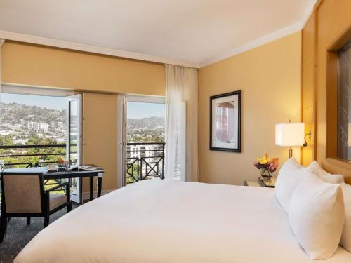 a bedroom with a bed and a desk with a window at Hotel Sofitel Los Angeles at Beverly Hills in Los Angeles