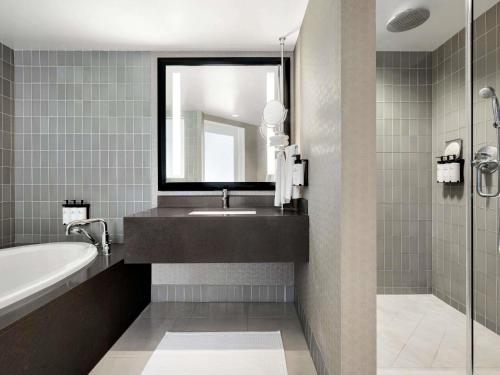 a bathroom with a sink and a tub and a mirror at Hotel Sofitel Los Angeles at Beverly Hills in Los Angeles