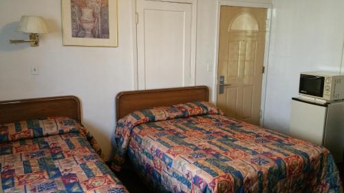 a bedroom with a bed and a microwave on a refrigerator at San Joaquin Motel in Merced