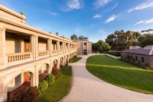 a building with a pathway next to a green lawn at Lancemore Mansion Hotel Werribee Park in Werribee