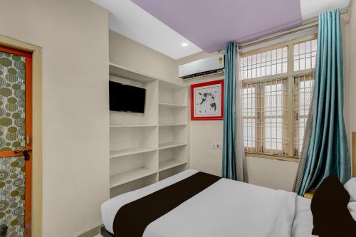 Un dormitorio con una cama y un televisor y una ventana. en Hotel O De Alphabet Home Stays@NTPC, en Rāmgundam