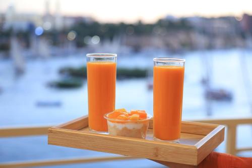 Crystala 2 guest house في أسوان: كوبان من عصير البرتقال وطبق من الفاكهة على صينية