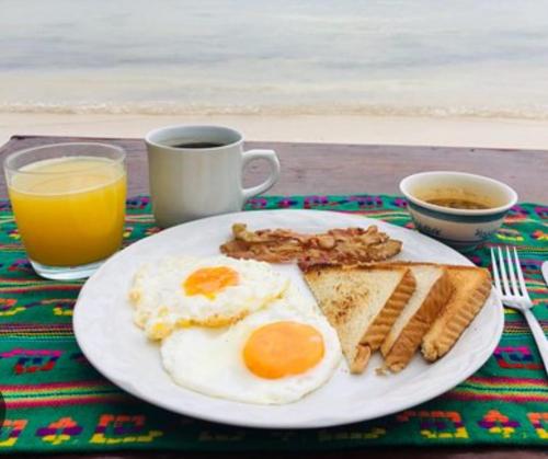 a plate of breakfast food with eggs bacon and toast at Mango Beach in San Bernardo del Viento