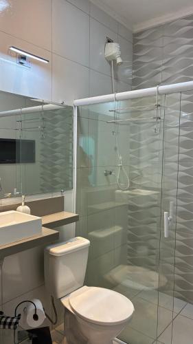 um banheiro com vaso sanitário e box de vidro em SR Casa de férias Astúrias no Guarujá