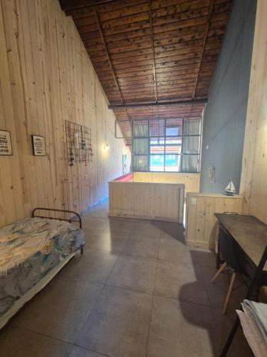 a room with a bed and a table in it at Chapa atrás - SalePatagonia in San Martín de los Andes