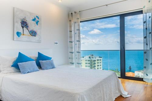 Un dormitorio con una cama blanca y una ventana grande. en Ocean Vista- T2 Funchal, en Bicas