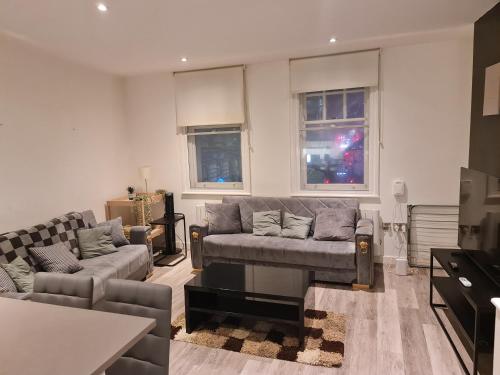 a living room with a couch and a table and windows at City Centre-Contactors-Professionals-Luxury Apartment in Nottingham