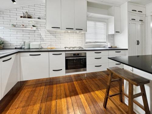 a kitchen with white cabinets and a wooden table at Cosy Cottage 4173 in Brisbane