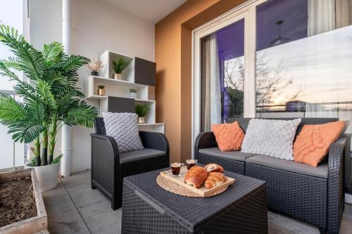 a patio with a couch and two chairs and a table at Le Magnifique - Grand balcon - Netflix - Grand Marché in Saint-Priest