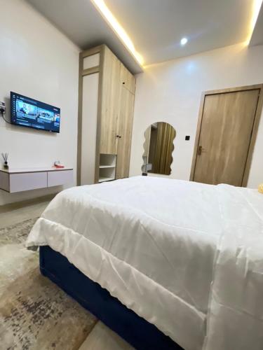 a bedroom with a white bed and a flat screen tv at 2-Bedroom Apartment with Pool, Gym, Tennis & Snooker in Lekki Ajah in Lekki