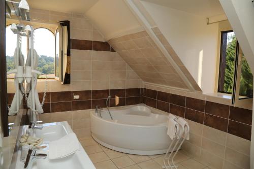 a bathroom with a tub and a sink at Hôtel-Restaurant Les Collines in Cublac