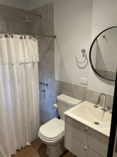 a bathroom with a toilet and a sink and a mirror at La Rosa Apartment in Adrogué