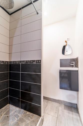 a bathroom with a shower with black and white tiles at L'Odyssée - Mercure - Gare - Wifi - Netflix in Tourcoing
