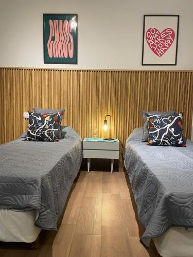 a bedroom with two beds and a table with a lamp at La Rosa Apartment in Adrogué