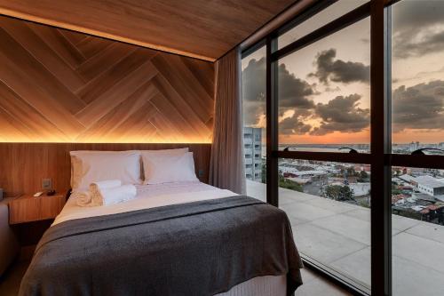 een slaapkamer met een bed en een groot raam bij New Time 1119 luxo e aconchego in Maceió