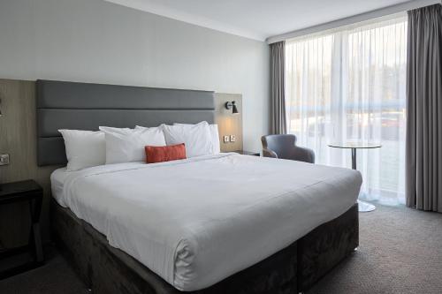 een hotelkamer met een groot bed met een rood kussen bij Holiday Inn Newcastle Gosforth Park by IHG in Newcastle upon Tyne