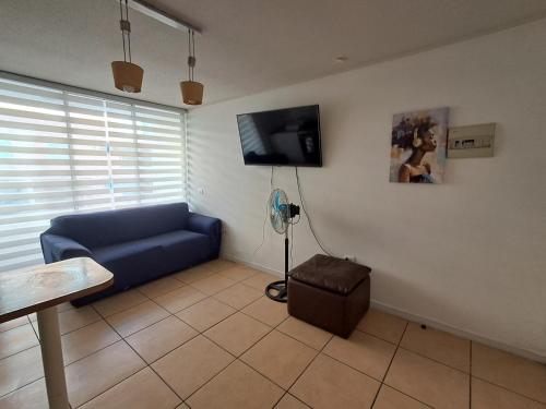 a living room with a blue couch and a flat screen tv at Sector Norte 1 Dormitorio in Antofagasta