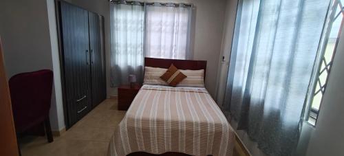 a small bedroom with a bed and a window at Purple Springs Elmina #1 in Esamang