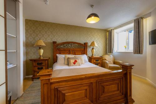 a bedroom with a large wooden bed and a window at The Hawk & Buckle Inn in Llannefydd