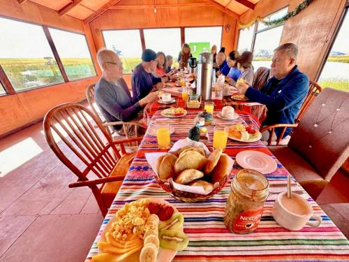 um grupo de pessoas sentadas à mesa com comida em Titicaca Origins Perú em Puno