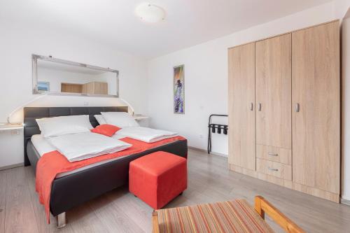 une chambre avec un grand lit avec un tabouret rouge dans l'établissement Apartment MaLa, à Bled