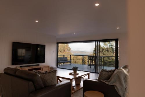 a living room with two chairs and a flat screen tv at House Peron - Bayside Luxury in St Helens