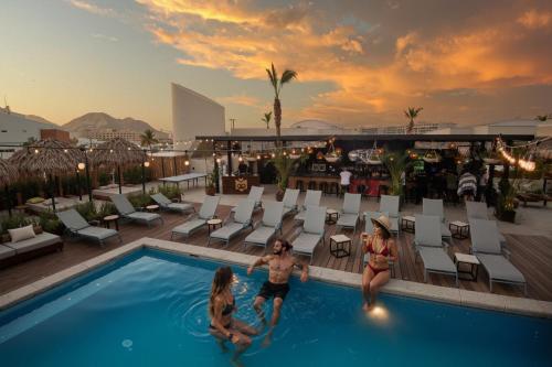 a group of people playing in a swimming pool on a roof at Mayan Monkey Los Cabos - Social Hotel in Cabo San Lucas