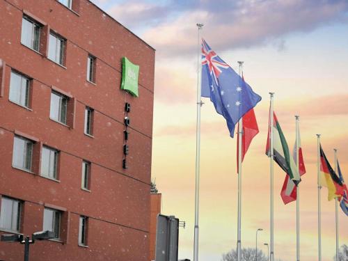 einer Gruppe von Flaggen, die vor einem Gebäude führen in der Unterkunft ibis Styles Warszawa Airport in Warschau