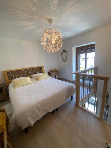 une chambre avec un grand lit et un lustre dans l'établissement La ferme des souvenirs 3, à Felleries