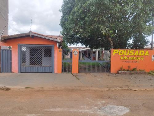 an orange building with a gate and a sign at Adventure Casa de Temporada in Chapada dos Guimarães