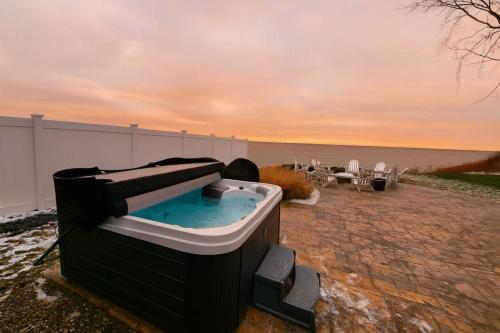 Oakwood Beach - Lake Front - Geneva-On-The-Lake في أشتابولا: وجود حوض استحمام ساخن على فناء بجوار المحيط