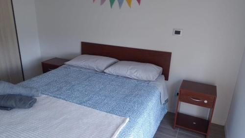 ein Schlafzimmer mit einem Bett mit einer blauen Decke und einem Nachttisch in der Unterkunft Departamento Céntrico Valdivia,Isla Teja in Valdivia