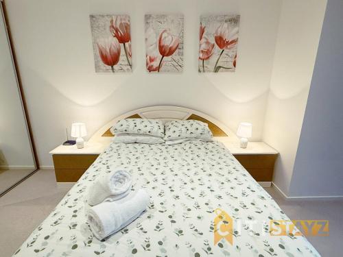ein Schlafzimmer mit einem Bett mit Handtüchern und Gemälden an der Wand in der Unterkunft Manhattan Magic - City 1Bd Retreat and Parking in Canberra