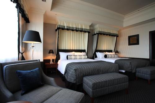 a hotel room with two beds and a couch at Hotel Monterey Grasmere Osaka in Osaka