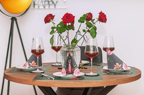 a table with wine glasses and a vase with roses at Motel Kalos in Haiger