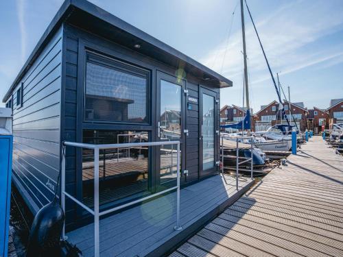 a small building on a dock next to boats at Luxury Houseboat Getaway in Uitgeest