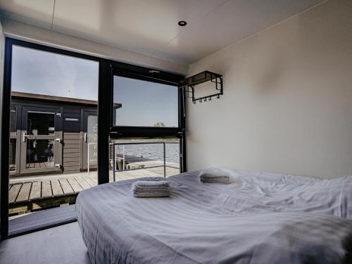 a bedroom with a bed and a large window at Luxury Houseboat Getaway in Uitgeest