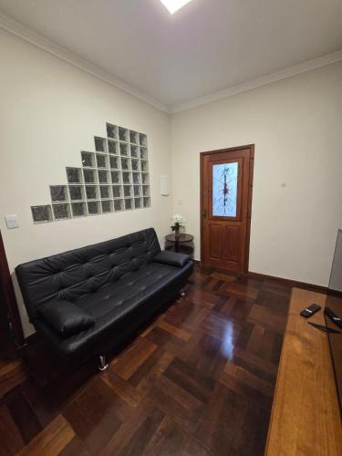 a living room with a black leather couch and a door at Casa do Mateus no bairro Pilar in Ouro Preto