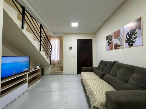 Una sala de estar con un sofá y un televisor de pantalla plana. en Casa Familiar - Próximo ao Aeroporto - WI-FI - Garagem Privativa GEM17, en Joinville