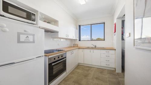 a kitchen with white cabinets and a window at Flynns Beach Seascape in Port Macquarie