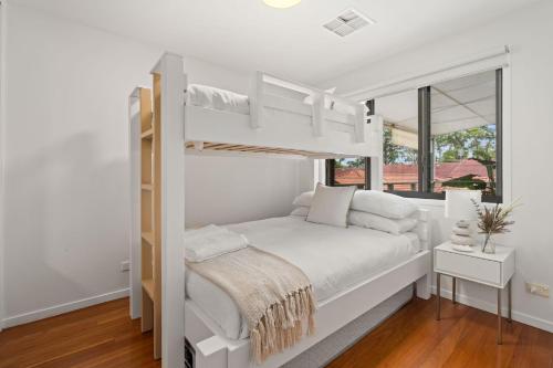 a white bedroom with a bunk bed and a window at Coast Bliss on Currambene in Huskisson