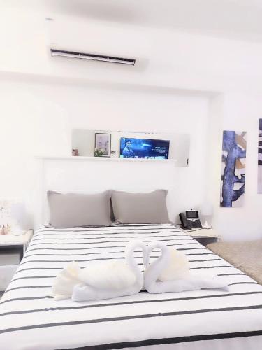 a white bedroom with a bed with two white pillows at aeon condon studio unit in Davao City
